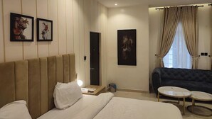A hotel room with a large bed, a sofa, two small tables, and artwork on the walls. - El-Castillo Hotels and Suites Lekki (Lekki)