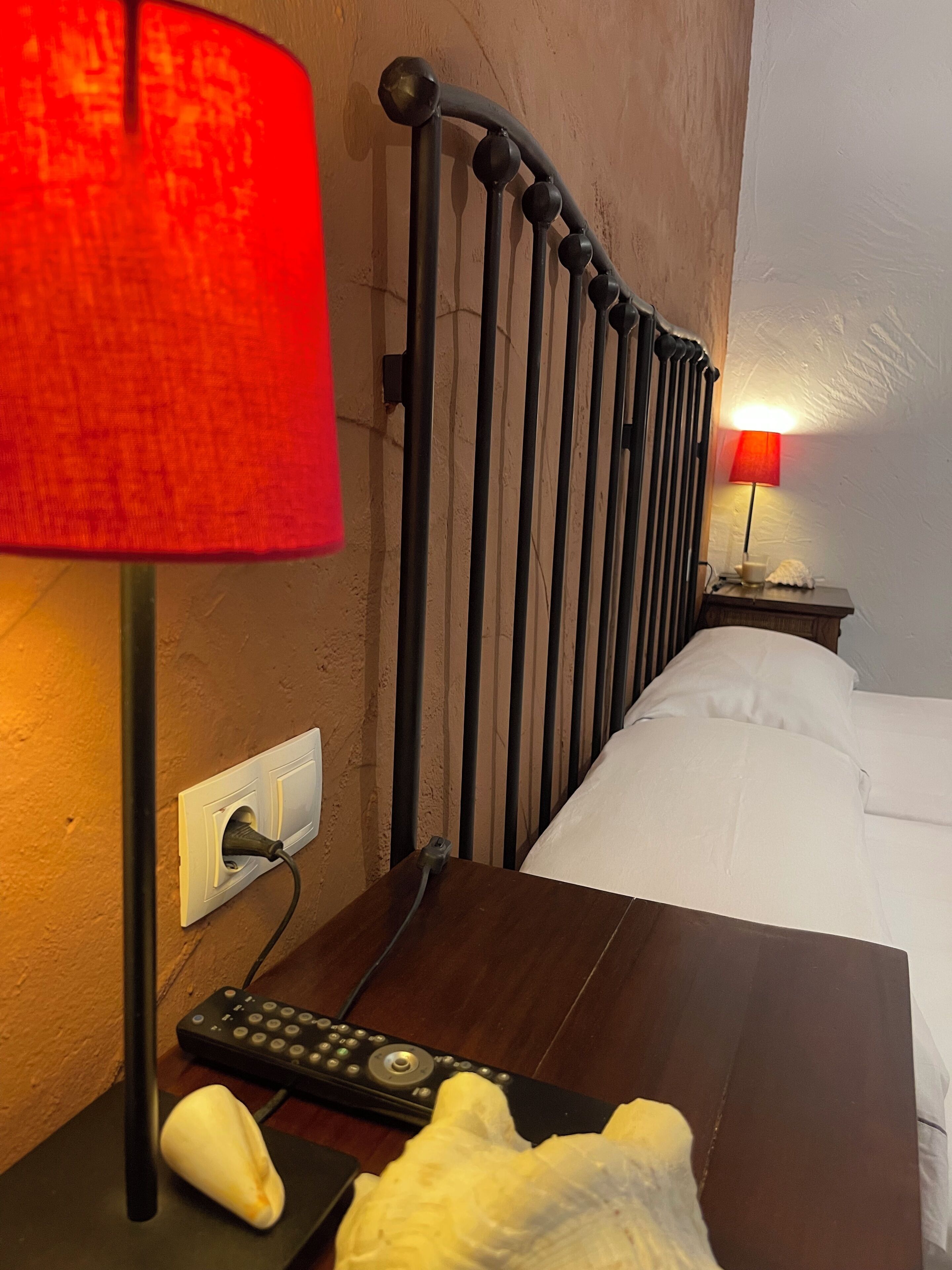 Une chambre d’hôtel avec un lit, une table de chevet avec une lampe, une télécommande et un téléphone.