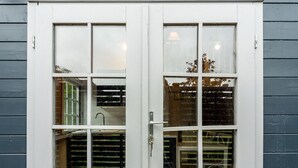 A white double door with glass panels, set in a gray building facade. - Walliswood Lodge - Rural Retreat - Newly converted, Wood Burner, Air Con, wi-fi (Dorking)