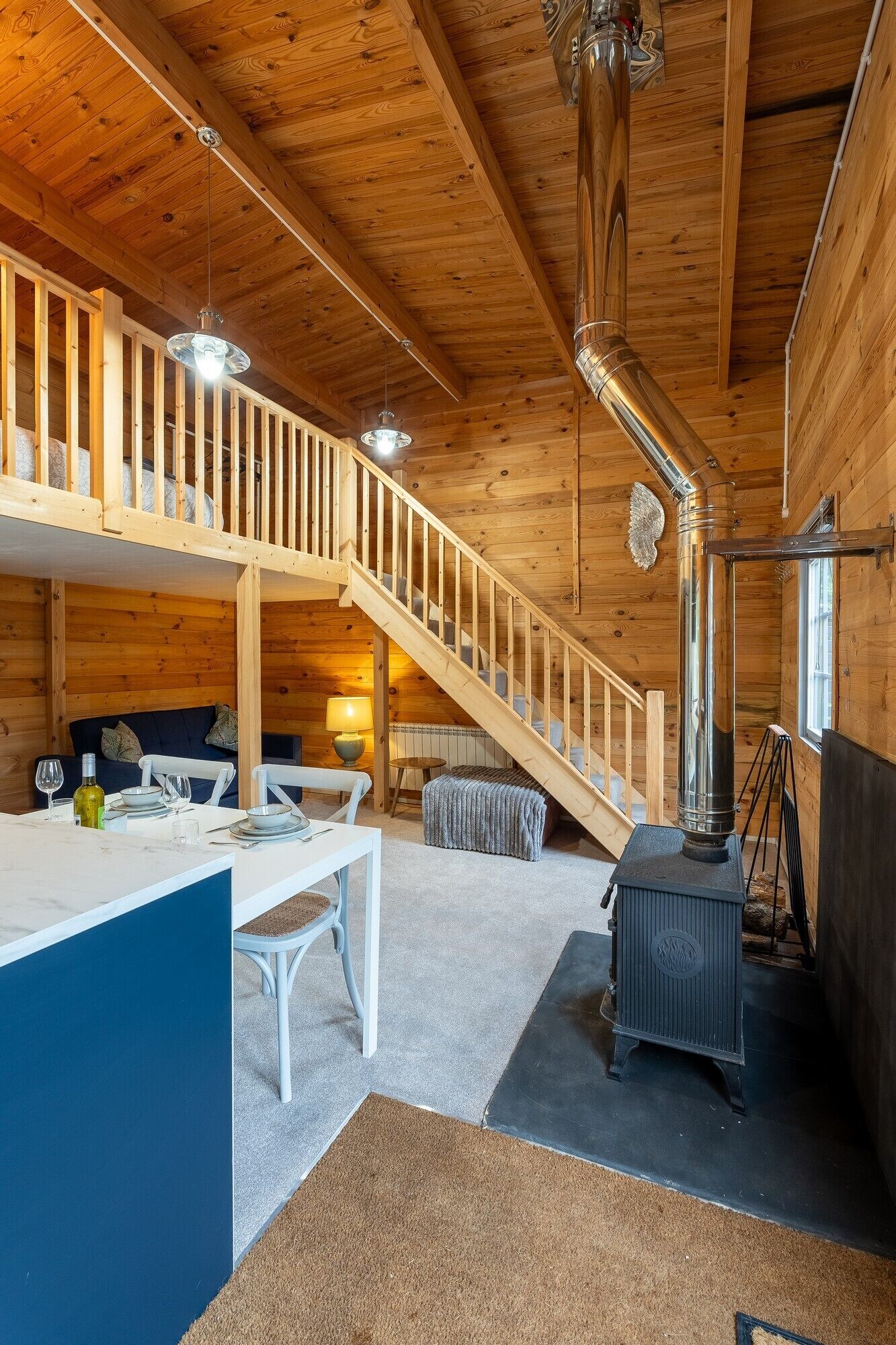 Een gezellig houten chalet interieur met een houten trap, een eethoek en een houtkachel.