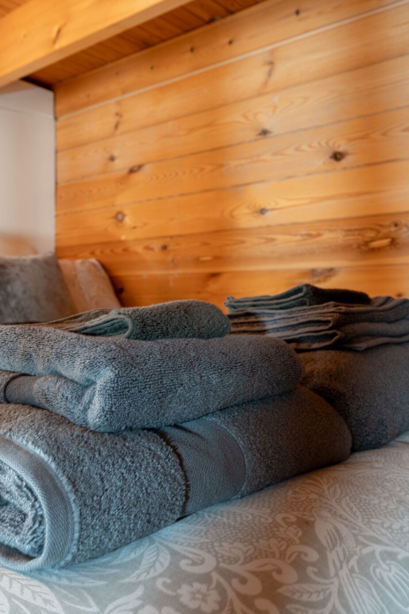A wooden ceiling with visible beams and a patterned fabric on the bed.