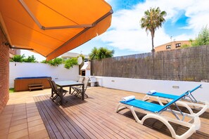 Relax and socialize in this outdoor patio area with a barbecue grill, table, and lounge chairs.