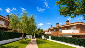Un barrio residencial con un sendero pavimentado, casas de ladrillo y setos bien cuidados.