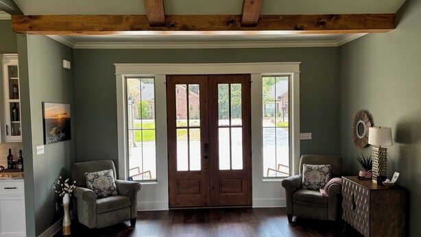 A spacious living room with a wooden ceiling, two windows, a door, and a fireplace. - Beautiful New 4-bedroom home on Granada Golf Course in Hot Springs Village. (Hot Springs Village)