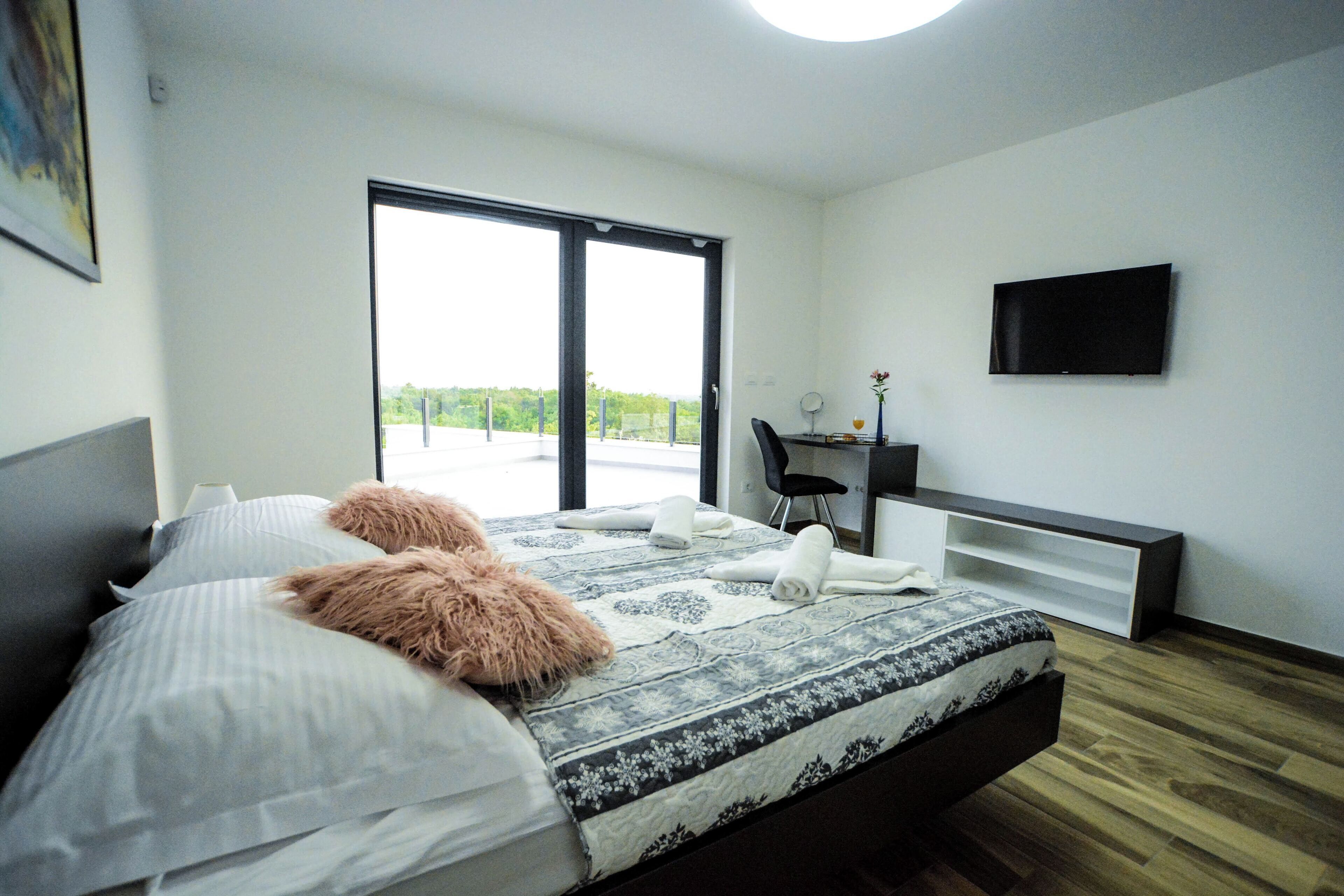 Ein modernes Schlafzimmer mit Bett, Schreibtisch und Fernseher.