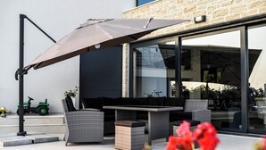 Eine Terrasss mit Korbmöbeln, einem Tisch und einem Sonnenschirm.