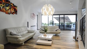 Ein modernes Wohnzimmer mit zwei Sofas, einem Couchtisch und einer außergewöhnlichen Pendelleuchte.