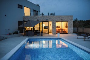 Uma casa moderna com piscina, móveis de exterior e um espaço de pátio.