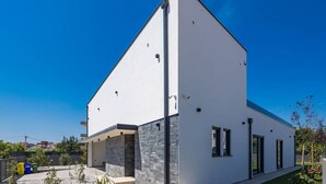 A modern two-story house with a white exterior and stone accents, featuring a large garage and a fenced backyard. - Villa Endi 4* with swimming pool in Medulin (Medulin)