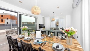 A modern dining area with a wooden table set for a meal, large windows, and a view of the outside. - Villa Endi 4* with swimming pool in Medulin (Medulin)