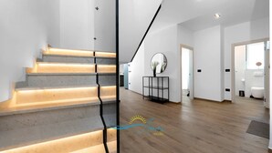 A modern interior with a staircase, a round mirror on a console table, and a wooden floor. - Villa Endi 4* with swimming pool in Medulin (Medulin)