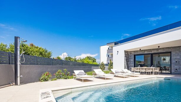 A modern house with a swimming pool, outdoor seating, and a large window overlooking the pool. - Villa Endi 4* with swimming pool in Medulin (Medulin)