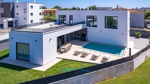 Une maison moderne dotée d’une piscine, d’un patio couvert et d’un espace repas séparé.
