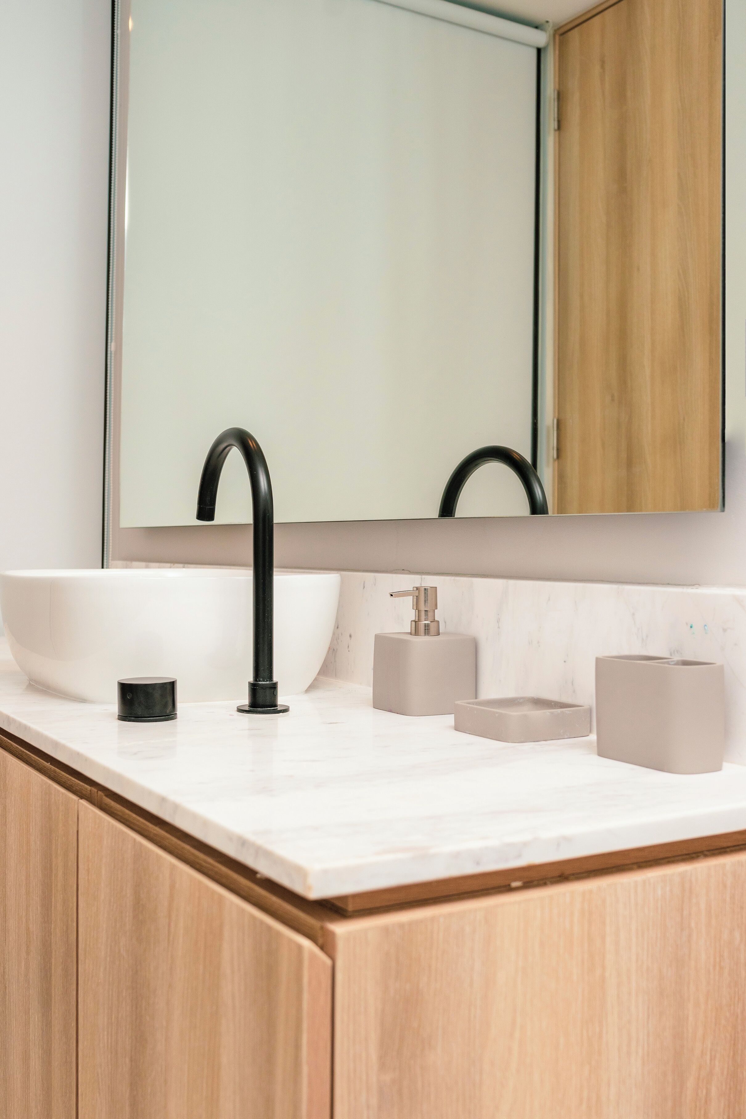 Une salle de bain moderne avec un grand lavabo blanc, un robinet noir et un miroir au-dessus.