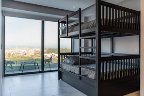 A modern room with a bunk bed, large windows, and a balcony with a table and chairs. - Exclusive Acapulco Apt With Beach Access (Acapulco)
