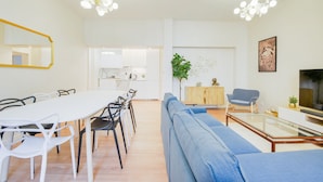 Ein modernes Wohnzimmer mit Essbereich, einer Couch, einem Fernseher und einer Pflanze.