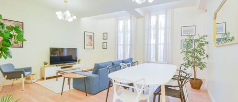 Relax in this stylish living room with a large dining table, comfortable sofa, and flat-screen TV.