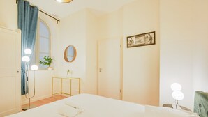 Ein Hotelzimmer mit Bett, Schreibtisch, Spiegel und einem Fenster mit Vorhängen.