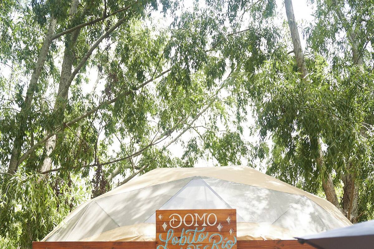 Une tente avec une pancarte indiquant « DOMO Lobo do Rio » et une personne debout devant.