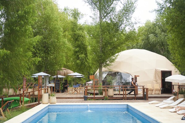 A pool area with lounge chairs, a tent, and a dining setup. - Brisas del lago Glamping (Partido de Tigre)