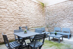 Eine Außenpatio mit Steinmauer, Tisch mit Stühlen und einer Bank.