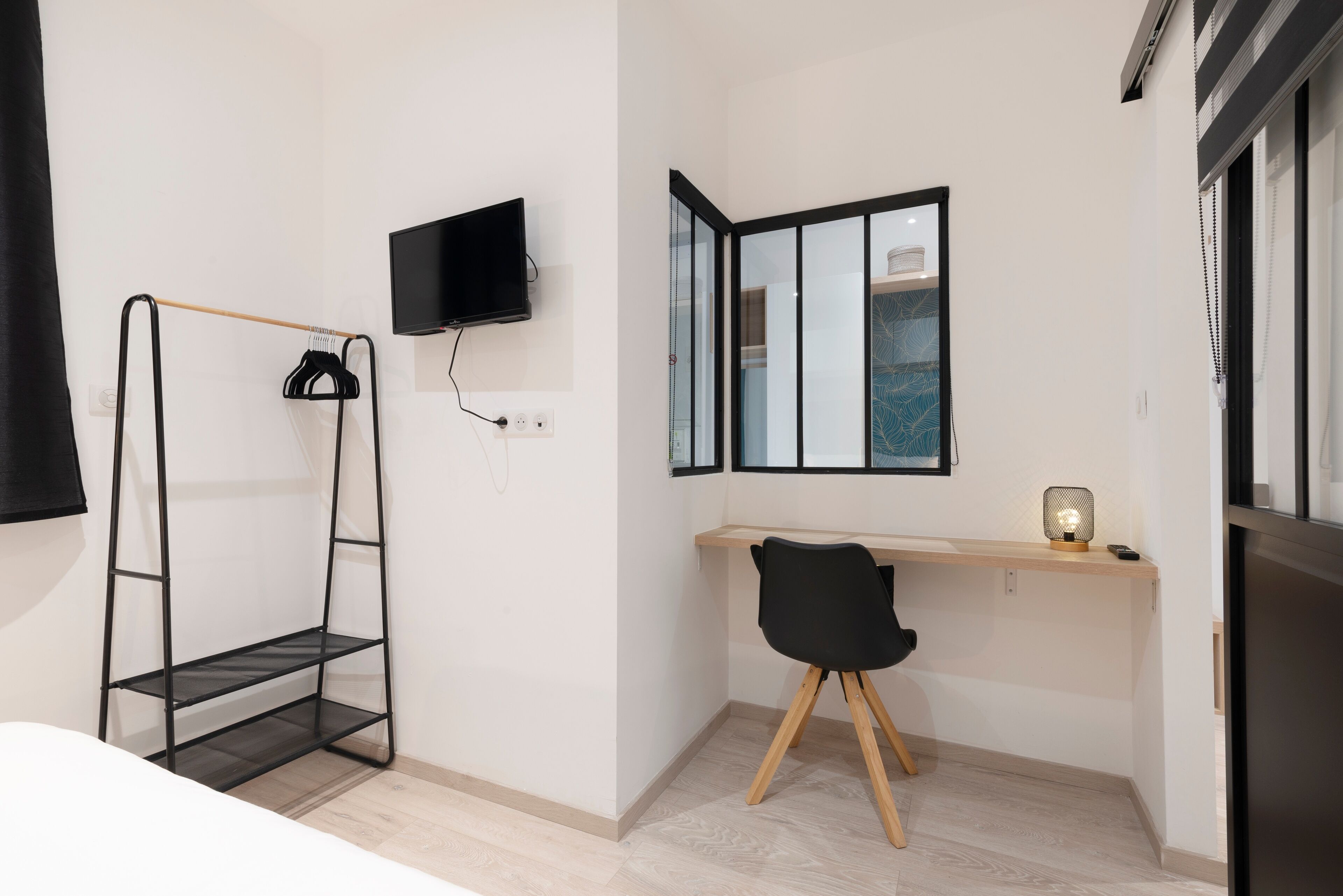 Une chambre moderne équipée d’un bureau, d’une chaise, d’une télévision et d’une étagère.