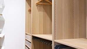A walk-in closet with wooden shelving, hanging space, and a shoe rack. - Le Spacieux de Dizier - Proche place des Vosges (Nancy)