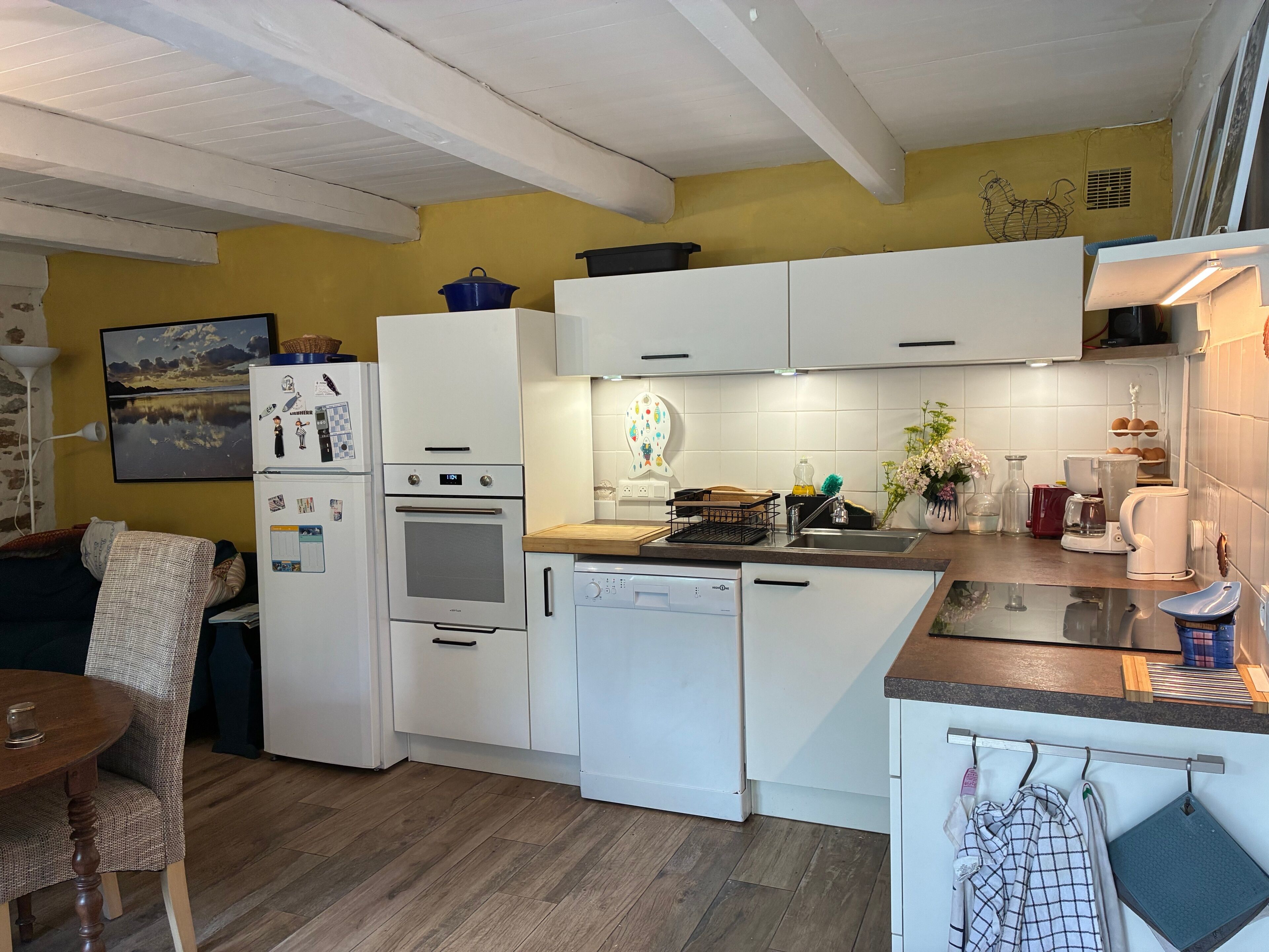 Une cuisine moderne avec des meubles blancs, un four encastré et un lave-vaisselle.