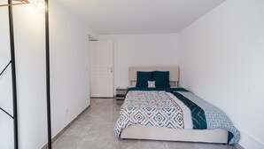 A bedroom with a bed, a bedside table, and a wardrobe. - Batié - Appt 4 personnes à Mulhouse (Mulhouse)