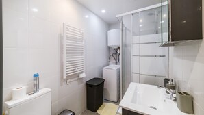 A modern bathroom with a white sink, mirror, and toilet. - Batié - Appt 4 personnes à Mulhouse (Mulhouse)