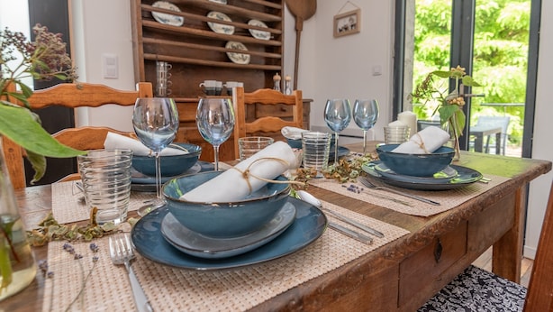 A dining table set with blue plates, glasses, and a rolled napkin. - L'appartement de Marie - Appt avec terrasse (Chalon-sur-Saone)