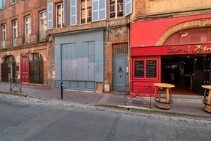 En gatubild som visar en stängd butik med ett rött markis och två pallar utanför.