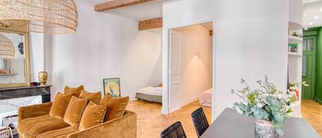 Ein modernes Wohnzimmer mit einer Couch, einem Esstisch und einer Pendelleuchte.