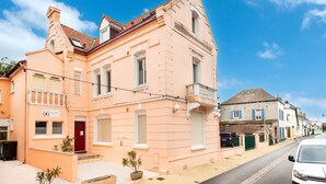 A pink building with a red door, a balcony, and a sign that reads "Villa Antonia."