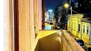 A narrow balcony with a view of a cityscape at night, including a tower and yellow buildings. - NIce Flat in Villa Near Old Town
 (București)
