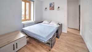 Quarto com cama, janela, radiador e soalho de madeira.