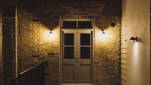 A brick wall with a double door and two wall-mounted lights. - Rockpool Cottage 5 Buckingham Mews Coastal Retreat (Broadstairs)