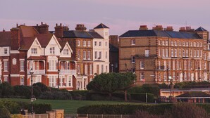 A row of terraced houses with a well-maintained lawn and hedges in the foreground. - Rockpool Cottage 5 Buckingham Mews Coastal Retreat (Broadstairs)