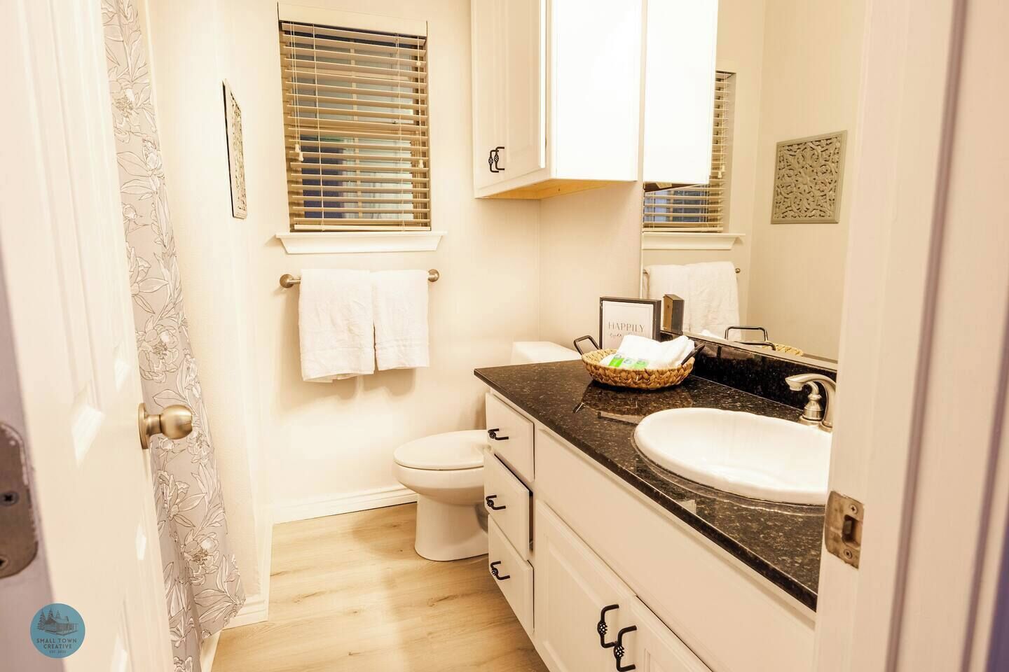 Ein Badezimmer mit Toilette, Waschbecken und Fenster mit Jalousien.