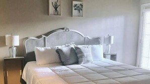 A neatly made bed with a white duvet, two bedside tables with lamps, and two wall-mounted pictures.