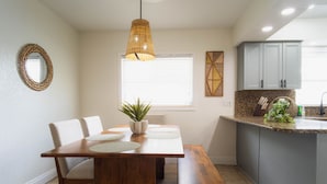 Un comedor con una mesa de madera, sillas y una lámpara colgante.