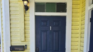 Een voordeur met donkerblauwe verf, een geel buitenschil en een welkomstmat.