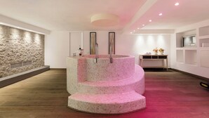 A modern interior with a circular mosaic staircase, a stone wall, and a wooden floor. - Villa Castiglione 9, Emma Villas (Castiglione della Pescaia)