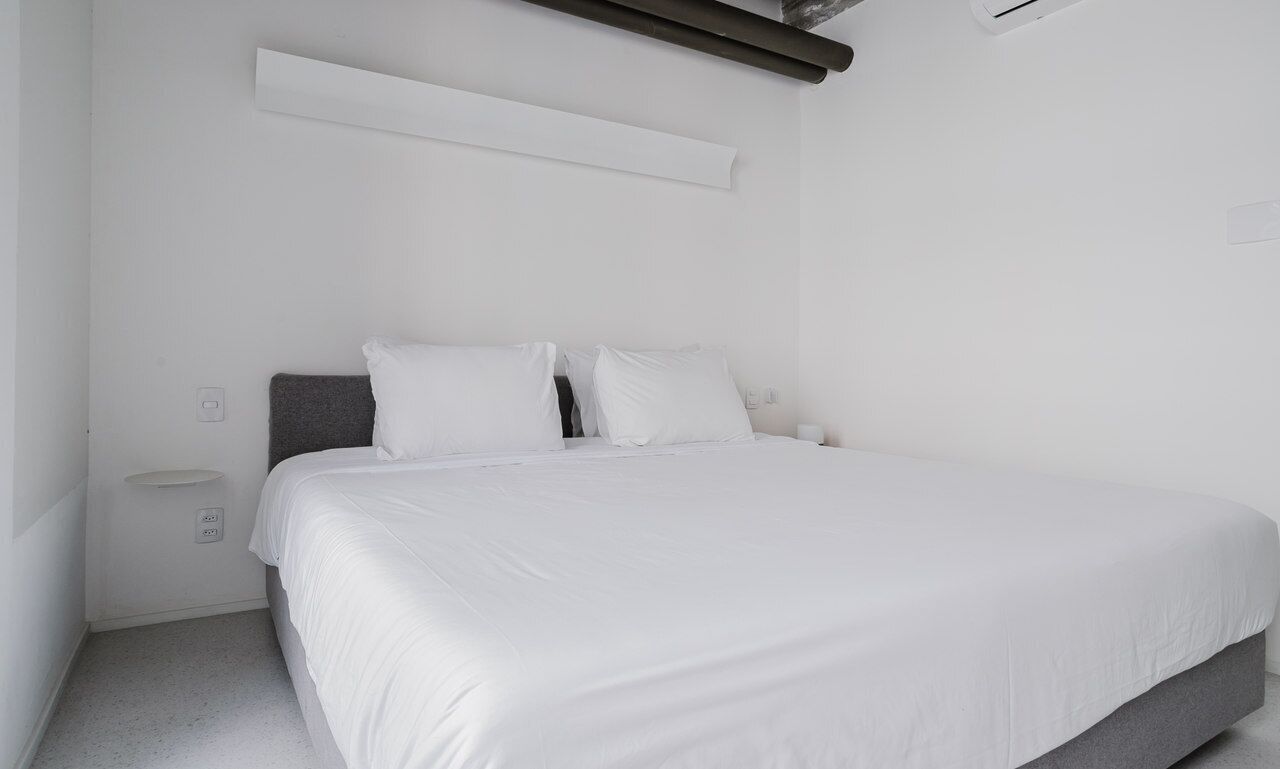 A modern bedroom with a large bed, white bedding, and a minimalist design.