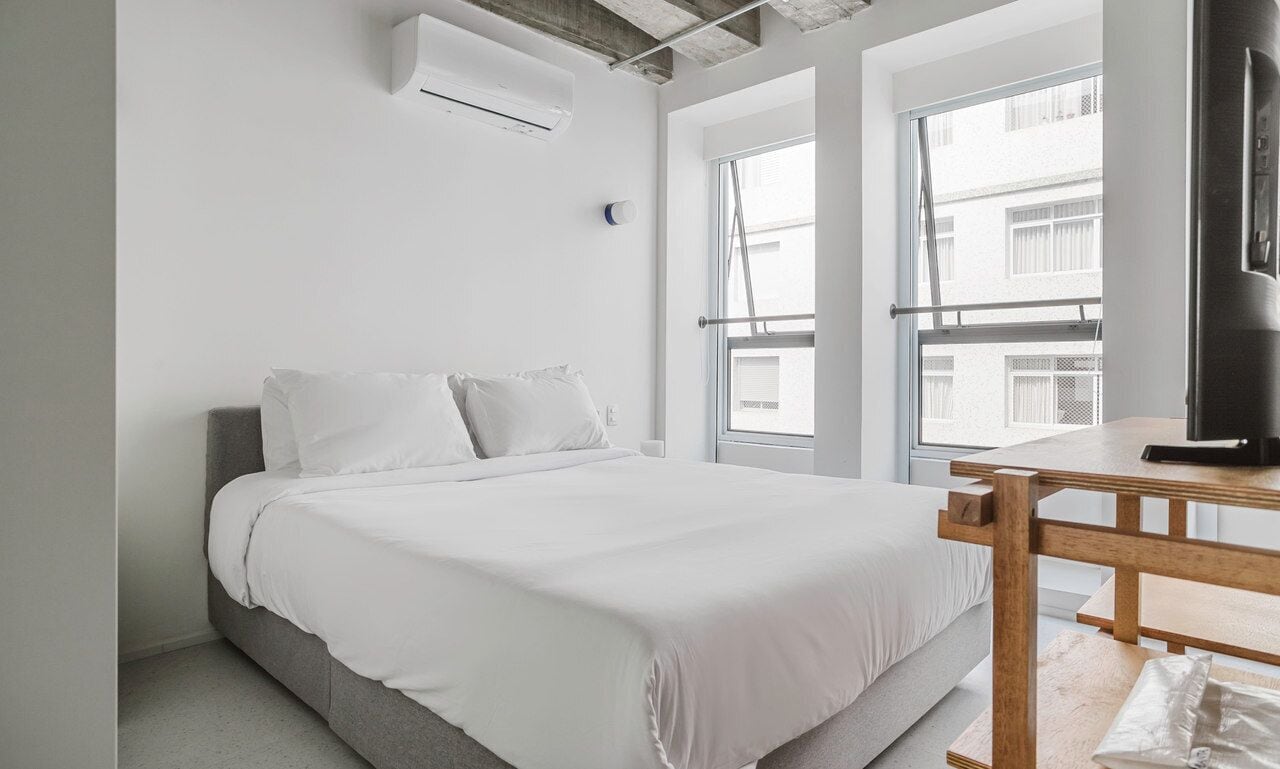 A modern bedroom with a large bed, a wooden table, and a TV.