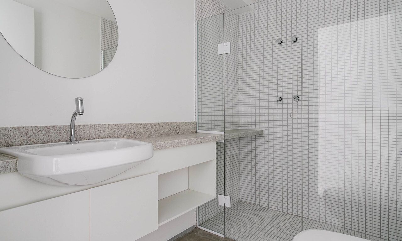 Un baño moderno con lavamanos, espejo y zona de ducha.