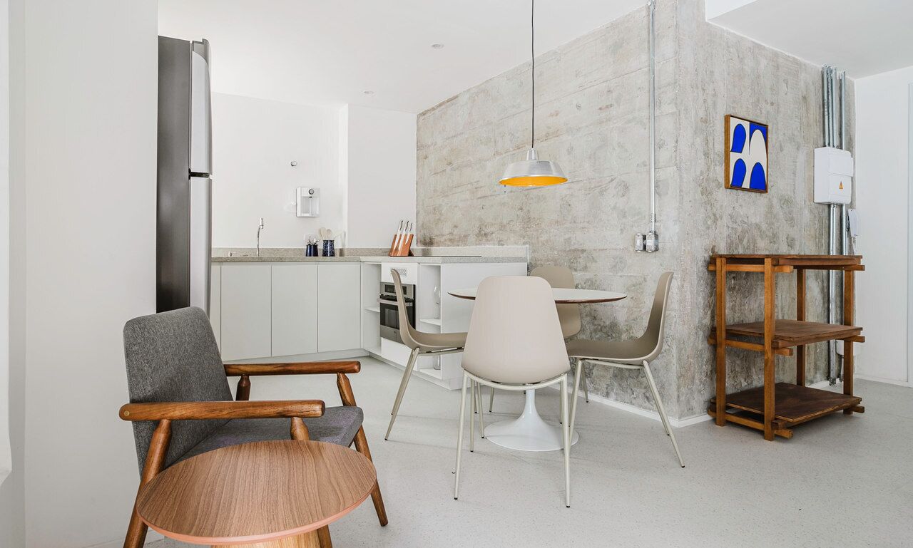 Une cuisine moderne avec des meubles blancs, un réfrigérateur en acier inoxydable et un coin repas comprenant une table ronde et des chaises.