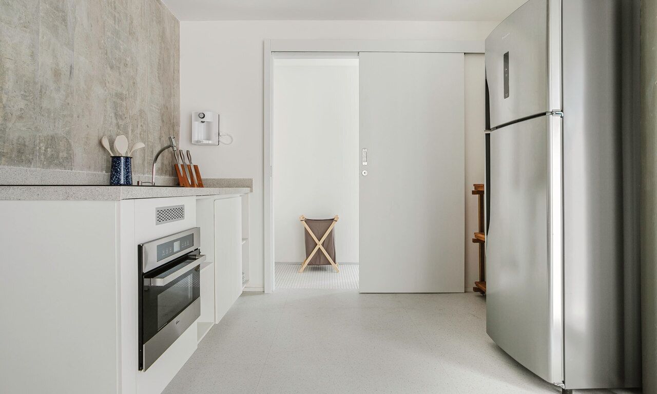 Una cucina moderna con frigorifero in acciaio inox, forno integrato e macchina del caffè.