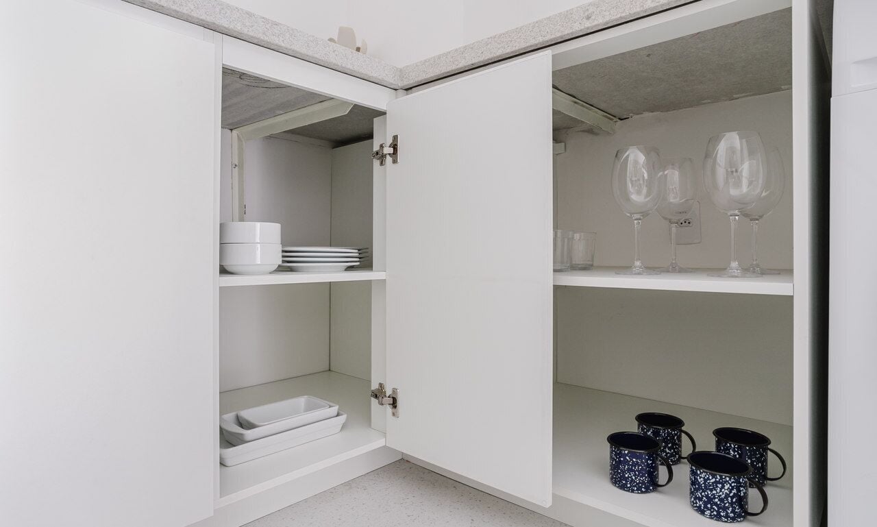Un armario blanco con puertas abiertas mostrando estantes de almacenamiento.