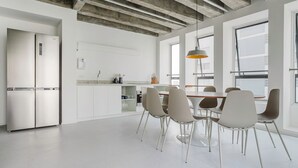 Eine moderne Küche mit weißen Schränken, einem Edelstahl-Kühlschrank und einem Essbereich mit Tisch und Stühlen.